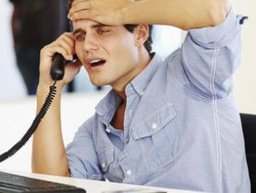 A man on a phone call is looking worried with his hand on his forehead 