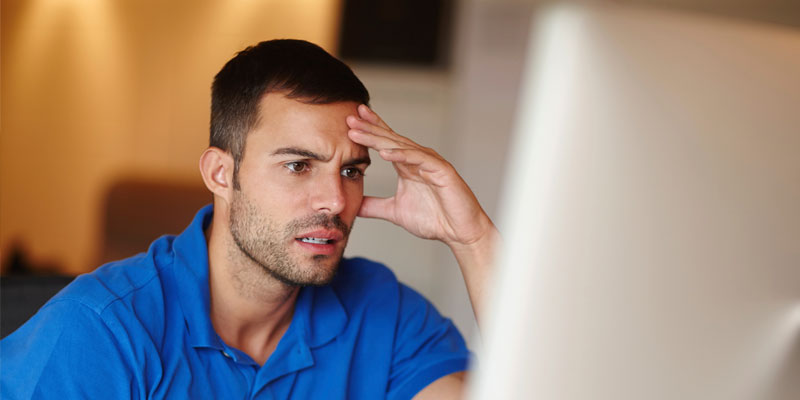 A man is looking worried with his hand on his forehead 